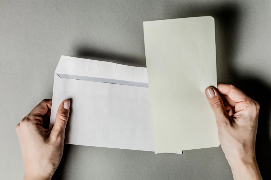 Due mani che tengono una busta aperta e la lettera appena estratta.