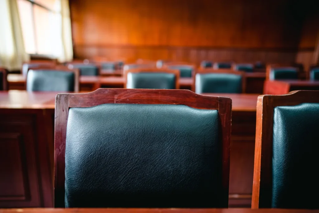 Le sedie vuote di un’aula di tribunale, con i banchi in legno sullo sfondo.